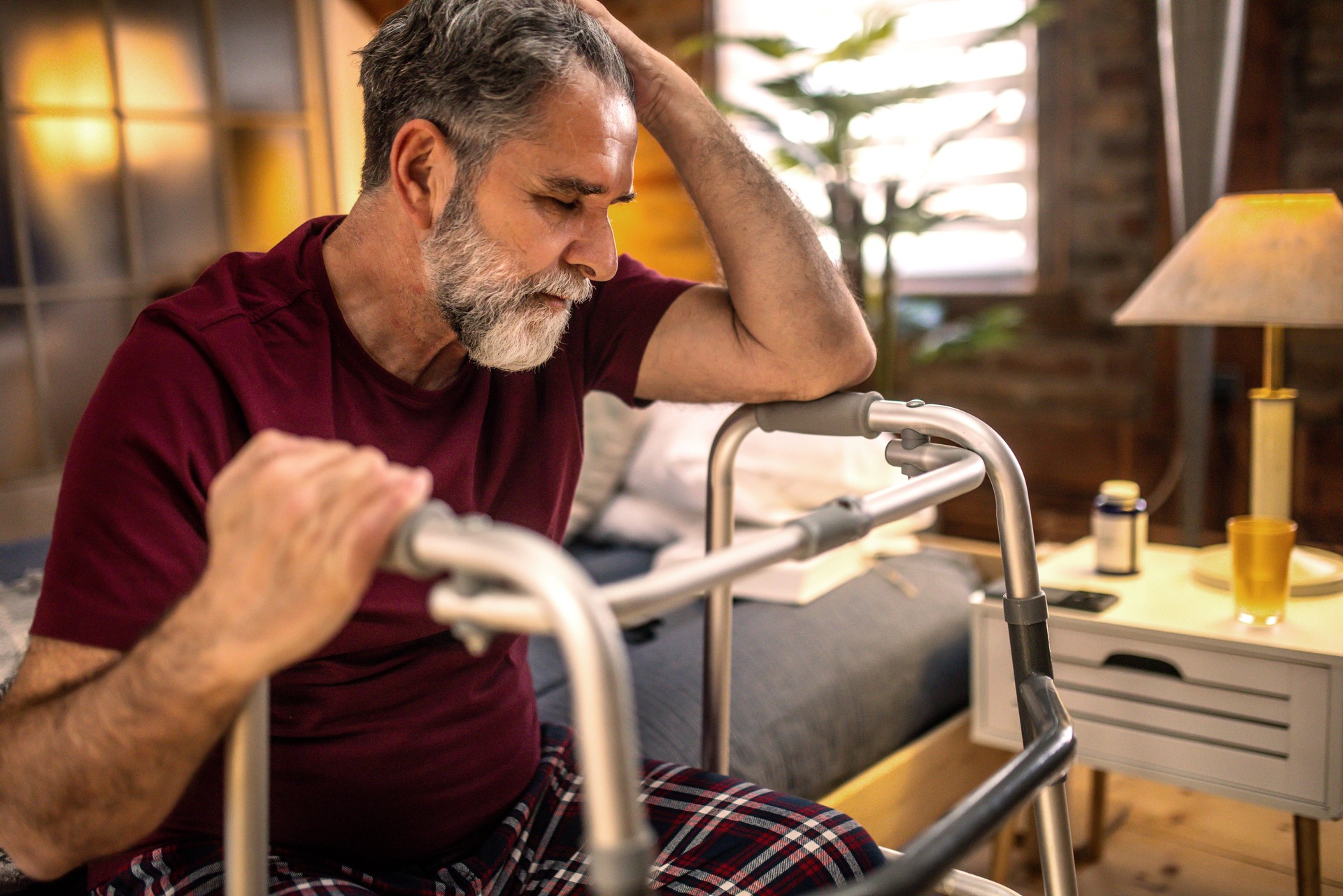 Thoughtful elderly man sitting alone at home with his walking cane